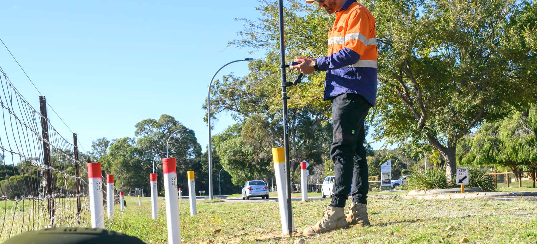 A Scope Mapping surveyor recording located services beside colour-coded marker posts